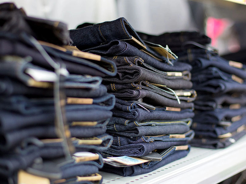 Stacked blue denim jeans neatly arranged on store shelves.