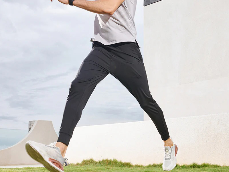 Man wearing lightweight black jogger pants while running outdoors, featuring tapered fit, stretch fabric, and performance design for active lifestyles.