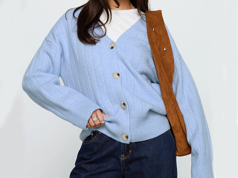 Woman wearing light blue ribbed cardigan with large buttons