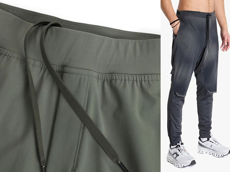 Close-up of black running pants showing zipper pocket and elastic waistband.