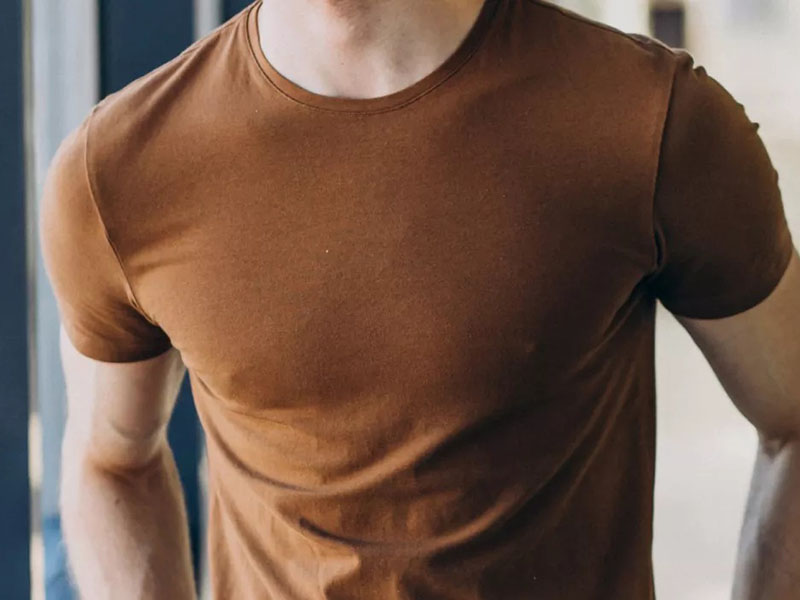 Close-up of a man wearing a high-quality brown cotton T-shirt, highlighting fabric texture and fit.