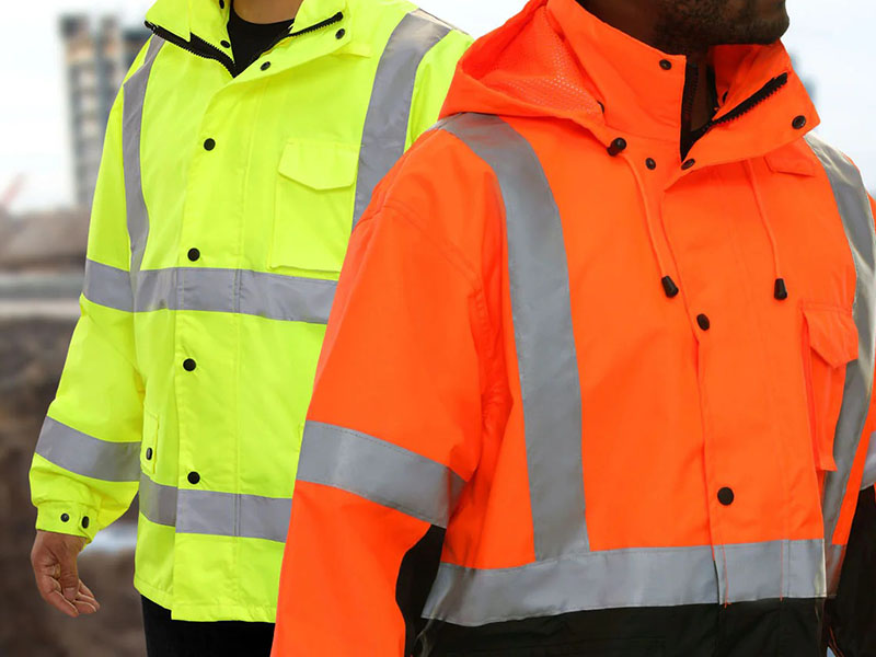 Workers wearing high-visibility safety jackets in fluorescent yellow and orange with reflective tape, designed for construction and industrial work environments.