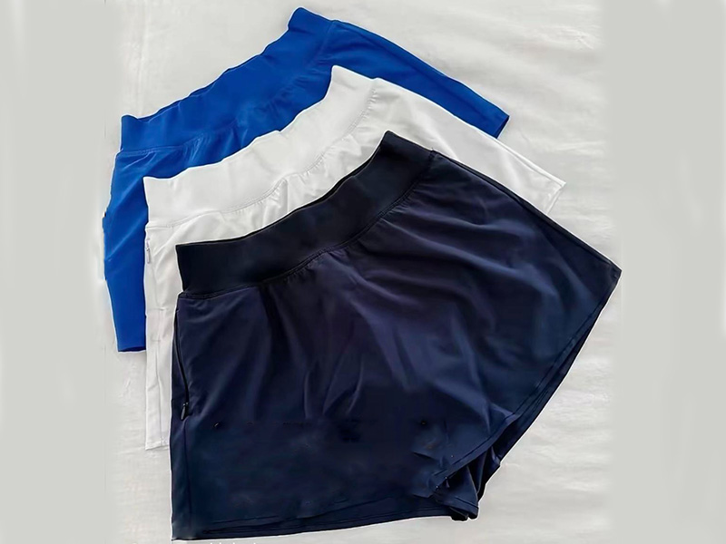 Three pairs of athletic shorts in blue, white, and black neatly laid on white surface.