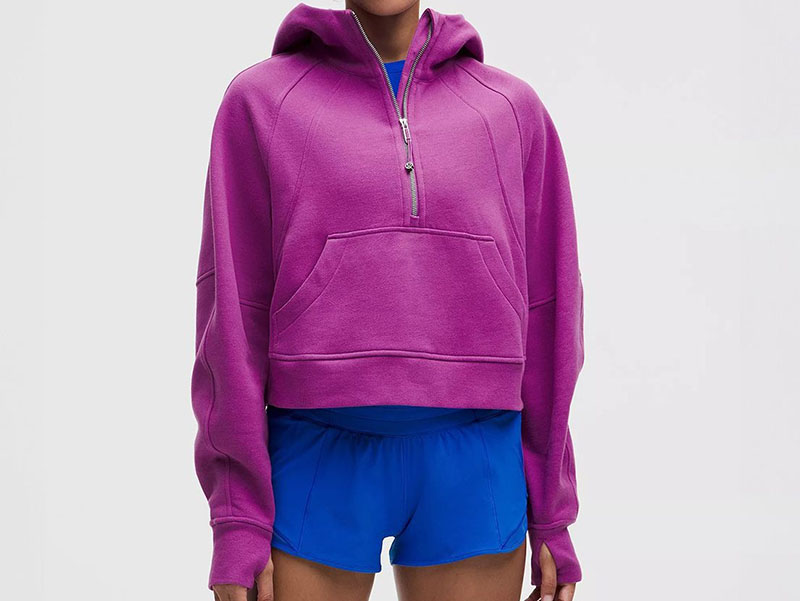 Woman wearing bright purple oversized half-zip hoodie with front pocket and relaxed fit, paired with blue athletic shorts, highlighting casual sporty style and comfort.