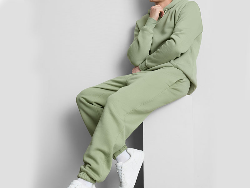 Person wearing a sage green hoodie and matching sweatpants, showcasing a comfortable fleece tracksuit with relaxed fit for casual wear and athleisure style.