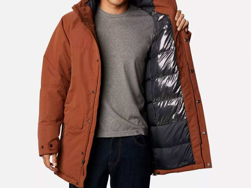 Man wearing brown insulated winter parka with hood and quilted inner lining for cold weather outdoor protection and casual style