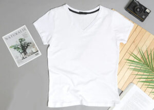 White V-neck T-shirt displayed flat with magazine, camera, book, and plant for lifestyle and promotional context