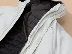 Close-up of white winter jacket with black quilted interior and zippered front detailing