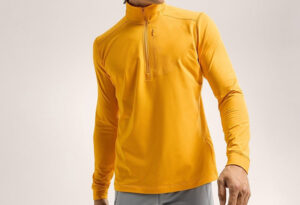 Man wearing a bright yellow long-sleeve half-zip athletic baselayer shirt against a plain background, standing with arms relaxed.
